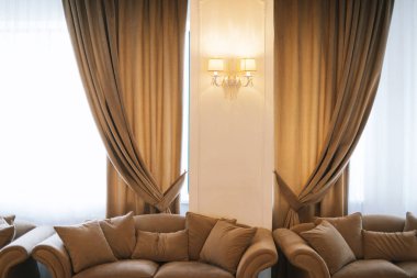 Fotoğraf Windows zarif perdeli ve kanepeler, otel odasında duvar lambası 