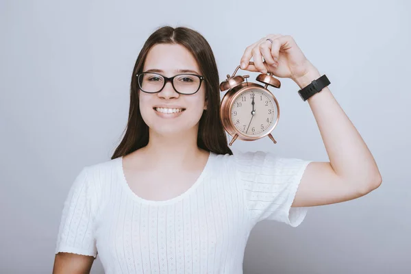 Bonita adolescente sosteniendo un reloj despertador y sonriendo al camer — Foto de Stock