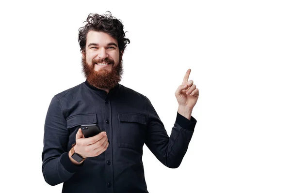 Homem Barbudo Inspirado Apontando Para Cima Segurando Telefone Celular Com — Fotografia de Stock