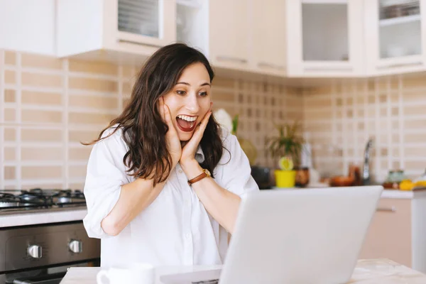 Una Joven Feliz Sentada Cocina Haciendo Una Cara Sorprendida Mientras — Foto de Stock