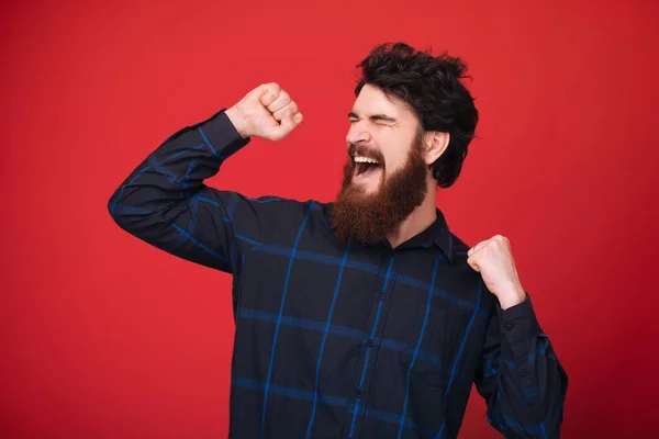 Photo of excited man with beard, celebrating, doing a victory gesture with rised hands