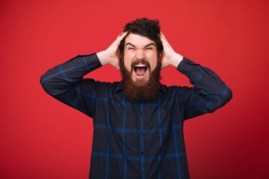 Yakışıklı sinirli sakallı adam, kırmızı duvar arka plan üzerinde çığlık 