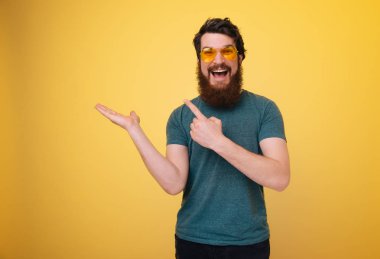 Gözlük içinde heyecanlı sakallı adam fotoğraf, boşaltmak işaret ve kamera bakıyor 