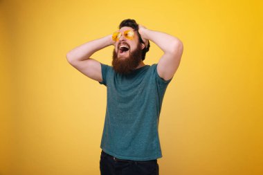 Kafası, baş ağrısı ve acı, izole sarı arka planda elleriyle sakallı adam çığlık 
