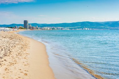 Şehir ve dağlar yakınında güzel bir Turistic plaj, mavi berrak su ve açık gökyüzü 