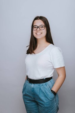 Beyaz arka plan üzerinde cep elleri ile gözlük giyen sevimli genç kadın smilling 