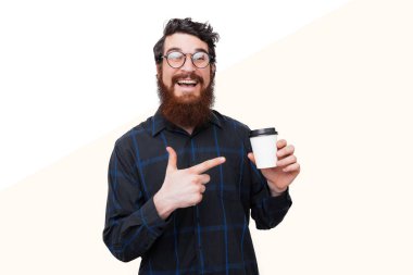 Rahat gülümseyerek sakallı mutlu adam portresi ve kahve fincan işaret To Go, beyaz duvar üzerinde duran