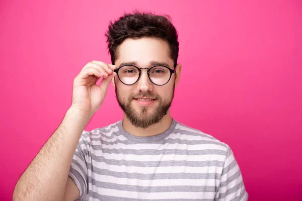 Foto Jovem Barbudo Tocando Quadro Óculos Liooking Câmera Sobre Fundo — Fotografia de Stock