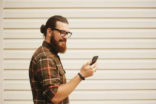 Bearded man looking at his phone, using face id, outside on whit — Stock Photo, Image