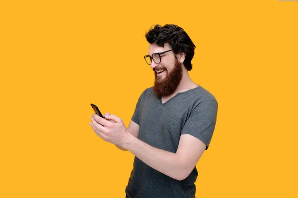 胡子的家伙使用智能手机在黄色背景的照片 — 图库照片