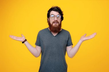 Glases sakallı adam fotoğrafı, yükselen elleri ile bilinmeyen jest yapıyor ve kameraya bakarak 
