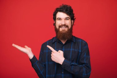 Kırmızı arka plan üzerinde elinde, copyspace işaret sakallı adam fotoğrafı 