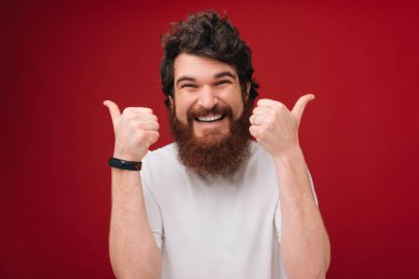 H andsome sakallı adam portresi ok sinyal, kırmızı bir arka plan üzerinde izole