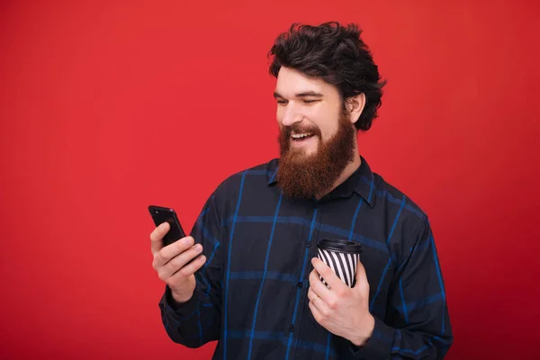 Skäggiga Kille Med Hjälp Smartphone Medan Håller Kopp Med Kaffe — Stockfoto