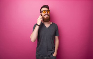 Izole pembe arka plan üzerinde arkadaşlarıyla telefonda konuşurken yakışıklı sakallı adam Portresi 