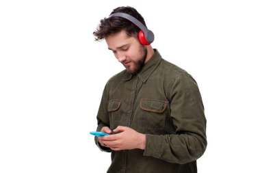 Cep telefonu kullanan ve kulaklıkla müzik dinleyen yakışıklı genç adamın fotoğrafı