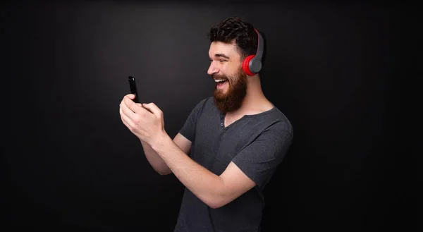 ひげを生やした幸せな男の写真 音楽を流し 孤立した背景の上に携帯電話を使用して — ストック写真