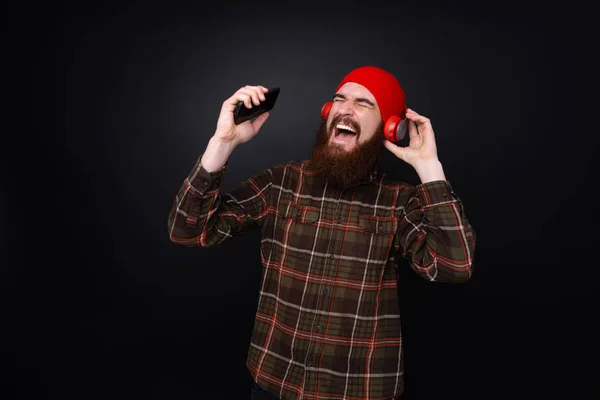 ヘッドフォンで音楽を聴いている幸せなひげの男の写真 ダール孤立した背景の上に立って — ストック写真