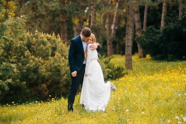 Just married couple having fun outdoor in park, beautiful bride and groom. Bride has lifted one leg from happiness.