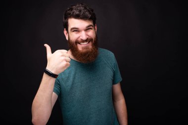 Gülümseyen heyecanlı sakallı adam başparmak gösteren 