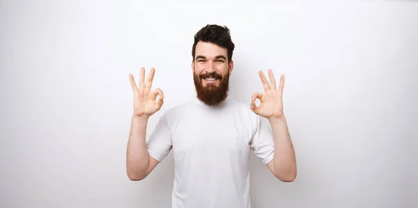 Portrait de jeune homme barbu montrant un geste OK sur fond blanc — Photo