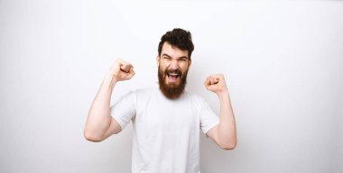 Beyaz t-shirt beyaz arka plan üzerinde başarı veya zafer kutluyor hayran sakallı adam portresi