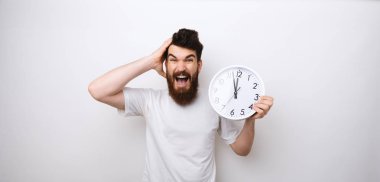 Bir sakallı adamın saat tutan portresi, gecikme ve disiplin konusunda endişeli 