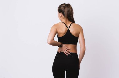 Genç Fitness kadın duygu sırt ağrı ayakta üzerinde beyaz duvar