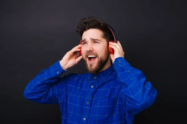 Retrato del joven sorprendido escuchando música en los auriculares — Foto de Stock