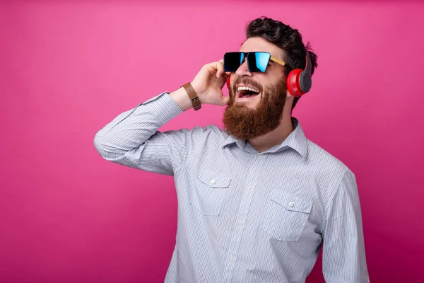 Sorprendido hombre hipster barbudo en casual escuchar música en los auriculares —  Fotos de Stock