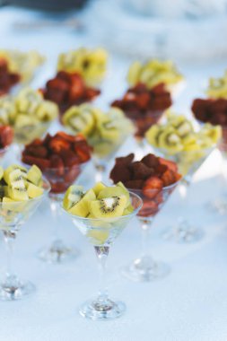 Beyaz bir masada gözlük servis kivi ve çilek gibi meyve dikey görüntü.