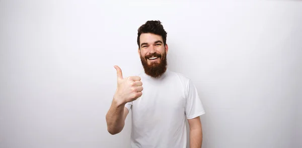 Jonge man met baard toont als gebaar met duim omhoog. — Stockfoto