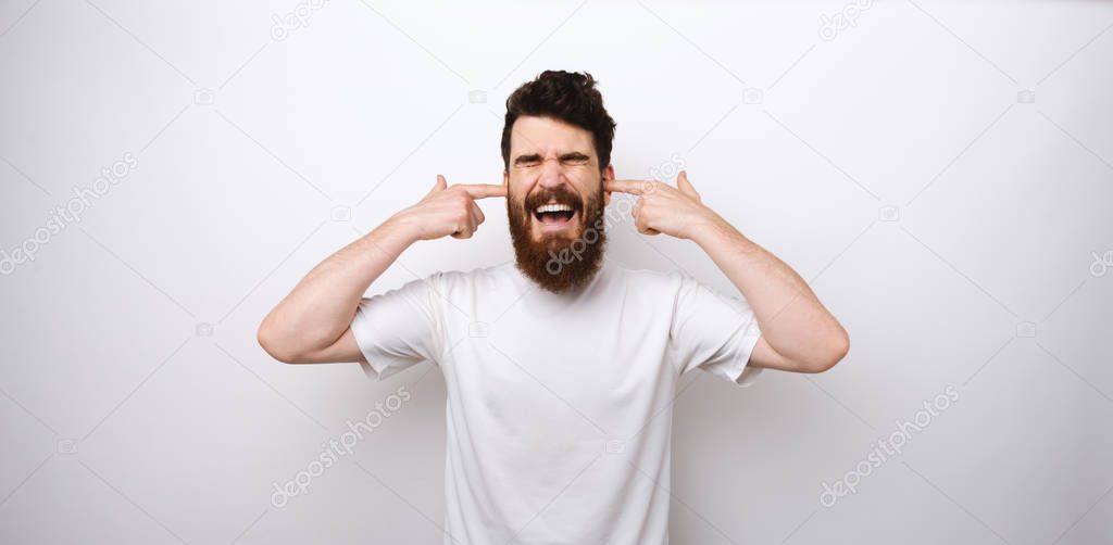 Bearded man doesn't want to hear anything. Covers his years and screams.