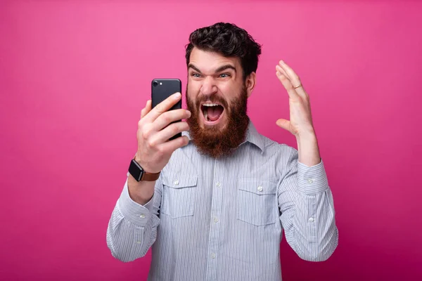 Jeune homme barbu choqué en regardant son téléphone geste . — Photo