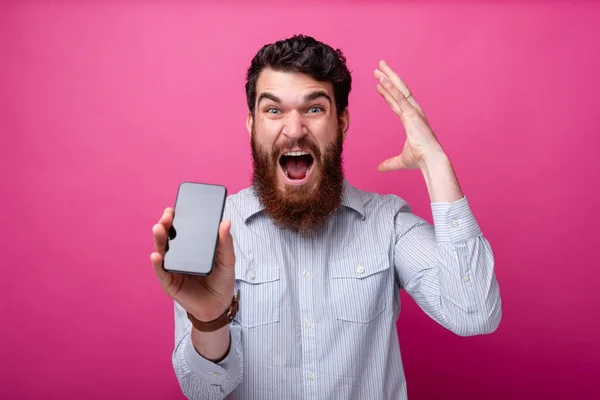 Sfoukni svůj rozum. Mladý vousatý muž zobrazující smartphone prázdnou obrazovku, gestikulující rukou u hlavy. — Stock fotografie