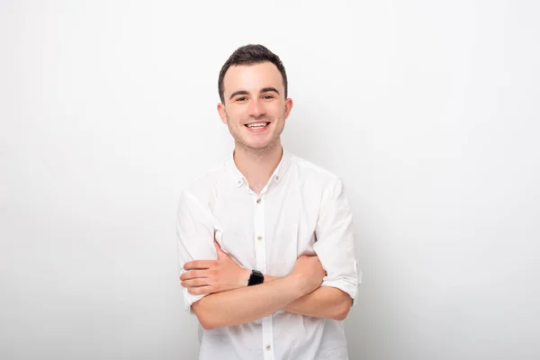 Portrait of a young smiling man with crossed arms on white background. — Stock Photo, Image