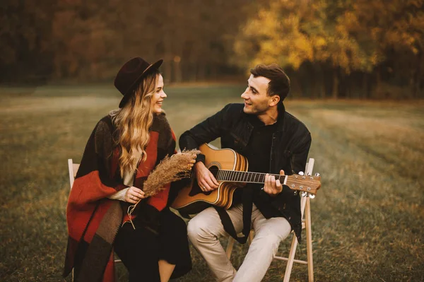 Preciosa pareja teniendo una cita en el parque y tocando en la guitarra —  Fotos de Stock