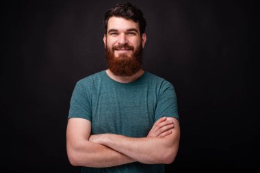 Kameraya bakan çapraz kolları ile gülümseyen genç adam portresi