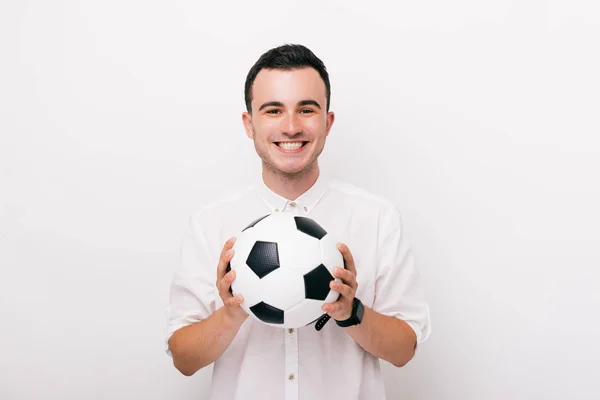 Porträt eines fröhlichen jungen Mannes mit Fußballball und Blick in die Kamera, der über einer weißen Wand steht — Stockfoto