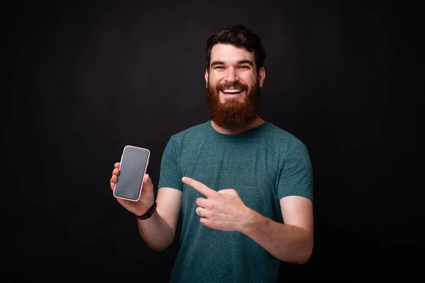 Retrato del hombre barbudo asombrado apuntando a su teléfono inteligente — Foto de Stock