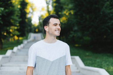 Taze neşeli genç adam uzaklara bakıyor, sabah parkta yürüyor.