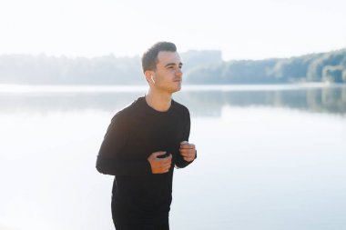 Genç sporcu si çalışan ve parkta müzik dinliyor.