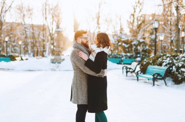 Mutlu genç aşıklar kışın parkta birbirlerine bakıyorlar.