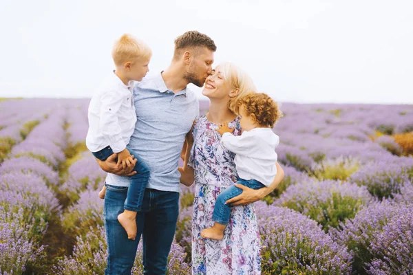 Beautiful family of four with two sons in a field of lavender. Parenting concept and family love. — Stock Photo, Image