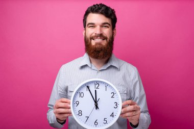 Büyük beyaz bir saat tutan sakallı gülümseyen adamın portresi