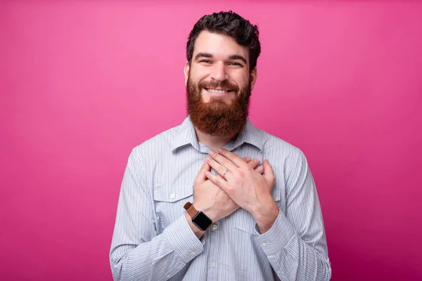 Lieve o mijn hart. Bearded man houdt zijn handen op zijn hart op zoek mooi op de camera op roze achtergrond. — Stockfoto