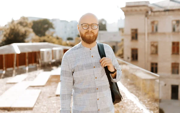 Photo d'un beau barbu portant des lunettes, debout sur une belle terrasse et regardant la caméra — Photo