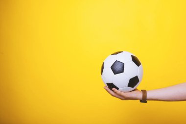 Yakışıklı kol fotoğrafı, sarı arka plan üzerinde, bir futbol topu tutan