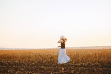 Yakışıklı genç bir kadın, eğleniyor ve buğday tarlasında koşuyor