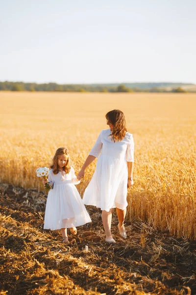 Buğday tarlasında yürüyen bir anne ve kızının fotoğrafı